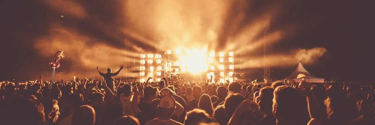 A festival crowd under golden stage lights, cropped into a continuous banner